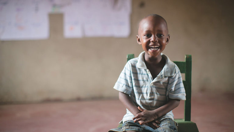 A young Ugandan boy smiling directly at the camera