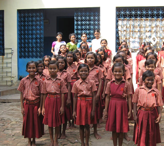 A group of smiling young Indian girls in red uniforms at the Surda Bethel project
