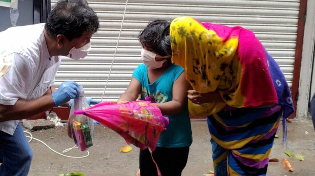 A man gives a young woman Covid relief supplies in India