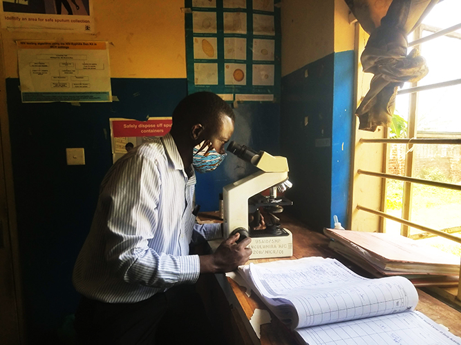 doctor looking through a microscope at the village medical center in uganda