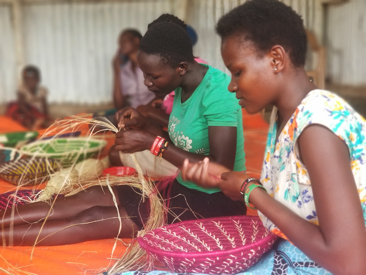 poor women in uganda learning to weave baskets