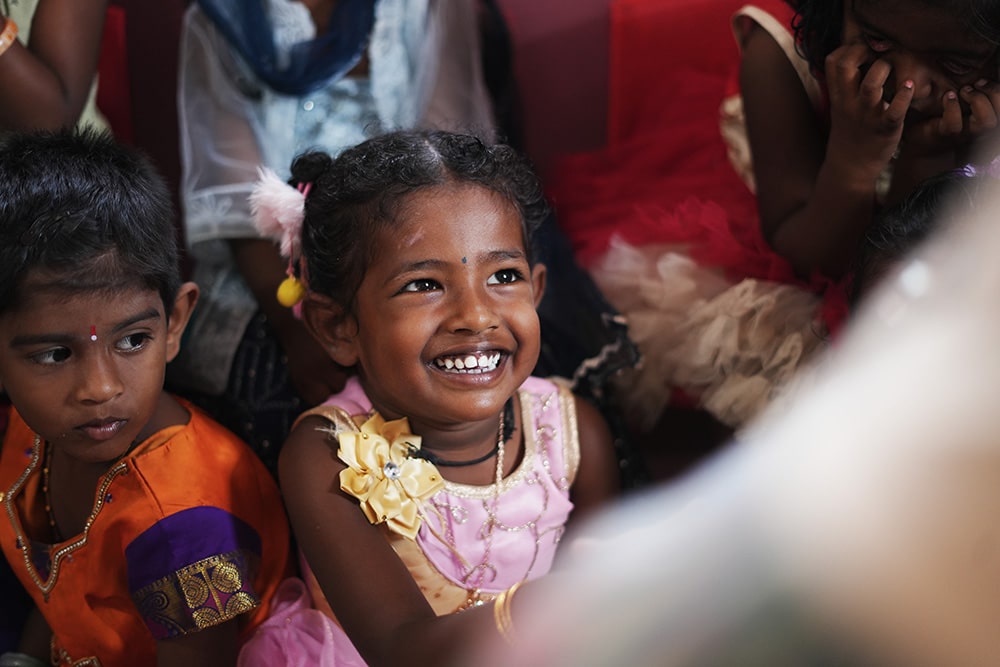 a Irula girl in a group smiling at the teacher