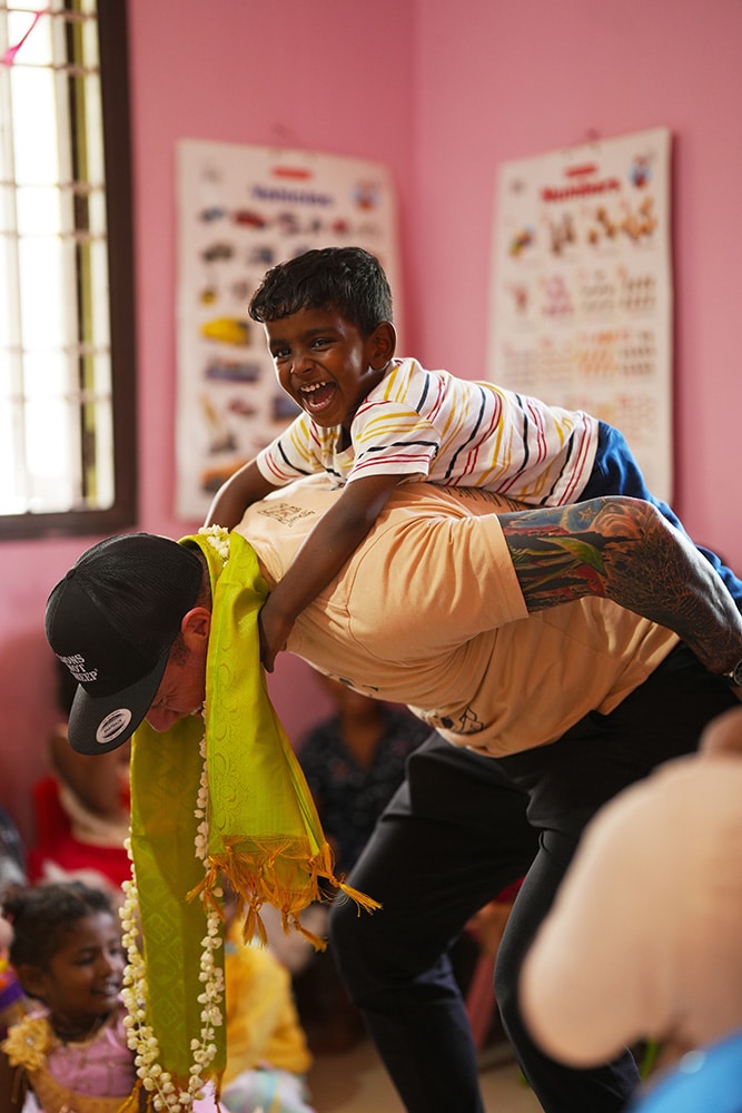 boy on back of worker laughing and playing at the Irula Children' Center